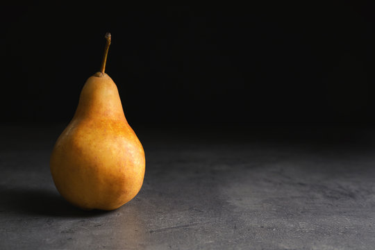 Ripe pear on table against black background. Space for text