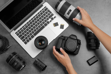 Woman with professional photographer equipment and laptop at gray table