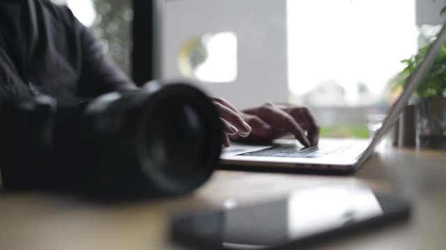 Close-up of a Man Hands use Laptop and Sony Camera at Cafe Table