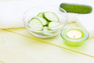Cucumber home spa and hair care concept. Sliced cucumber, bottles of oil, sea salt, bathroom towel. White board background