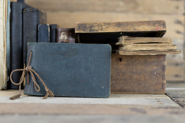 Old books and a wooden box set on a shelf. Old publishing houses set side by side on a wooden table.