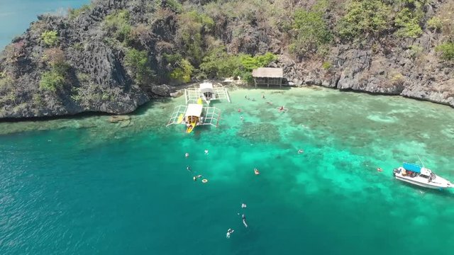 Aerial drone shot over people swimming, between paraw boats in beautiful, shallow, clear, blue water, at Coron island, in Philippines, Asia