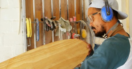 Surfboard maker examining surfboard 4k - Powered by Adobe