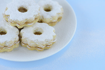 Homemade apricot jam Linzer on a white plate, pastel blue background
