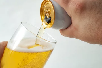 Papier Peint photo autocollant Alcool Concept de boisson alcoolisée, de consommation d& 39 alcool et de teneur en alcool avec gros plan sur une main qui coule d& 39 une canette de bière dans un verre clair isolé sur fond blanc