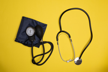Blood pressure monitor and stethoscope against orange background. Isolated medical accessories