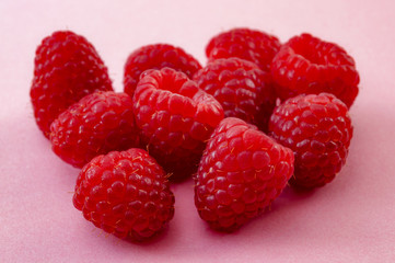 Vegetarian diet, summer raspberry fruits and healthy nutrition concept with close up on a pile of raspberries isolated on pink background