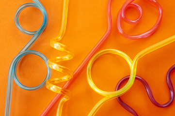 Minimalist image of colorful plastic drinking straws on a orange background