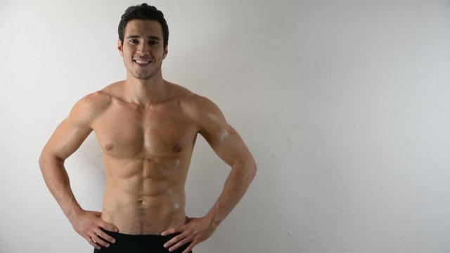 Handsome shirtless athletic young man in jeans, looking at camera in studio shot, on white background