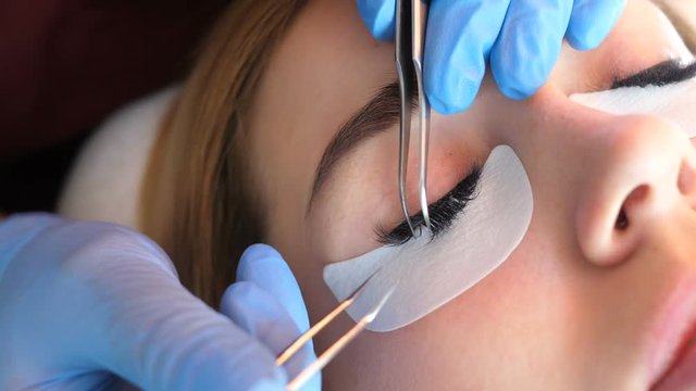 Artificial eyelash extensions from the master of eyelash extension in the beauty salon, medical tweezers hd