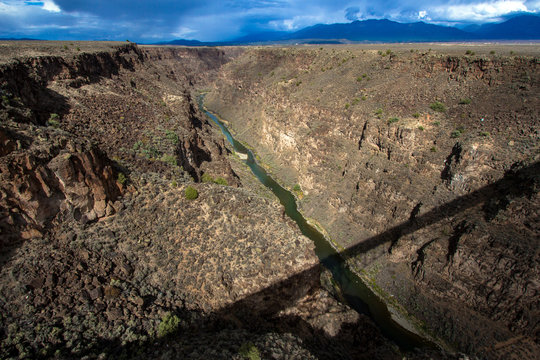 The bridge over the Rio Grande Gorge casts a long shadow across its 800' deep canyon, which lies on the Taos Plateau in New Mexico; looking north from US Hwy 64