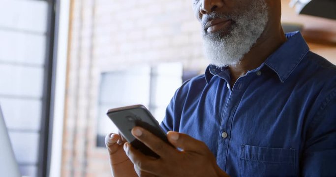 Senior man using mobile phone in kitchen 4k
