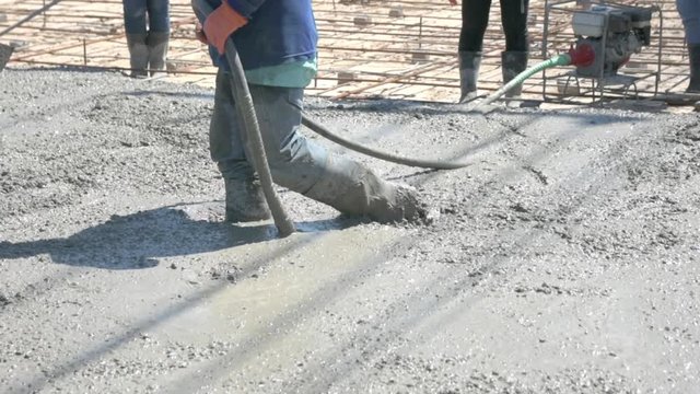 Workers in construction site using Vibration Machine for eliminate bubbles in concrete. after Pouring ready-mixed concrete on steel reinforcement to make the road by mixing mobile the concrete mixer.