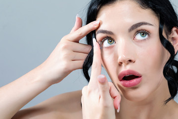 Young woman with contact lenses on a gray background