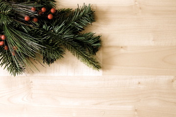 Faux fir tree branch and berries on wood background