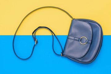 Beautiful women bag of blue leather on yellow and blue background. The view from the top. Flat lay.