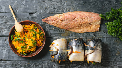 A bowl of steamed vegetables, the carcass of the mackerel and the three prepared loaf fish for baking. Flat lay.