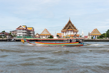 Fototapeta premium Boat floating on river along temples in Bangkok
