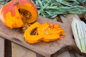 Orange pumpkin cut into pieces on wooden cutting board with pumpkin seeds. Butternut squash. Vegan vegetarian healthy food concept