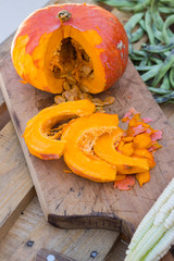 Orange pumpkin cut into pieces on wooden cutting board with pumpkin seeds. Butternut squash. Vegan vegetarian healthy food concept