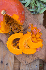 Orange pumpkin cut into pieces on wooden cutting board with pumpkin seeds. Butternut squash. Vegan vegetarian healthy food concept