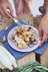 Woman hands holds and prickles with fork steamed, cooked vegetables. Cauliflower, mushrooms with paprika. Vegan lunch, vegetarian dinner, healthy food