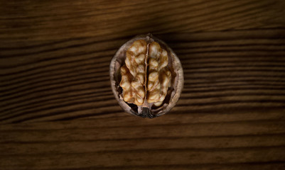 Walnut kernel shaped like brain on wooden background.