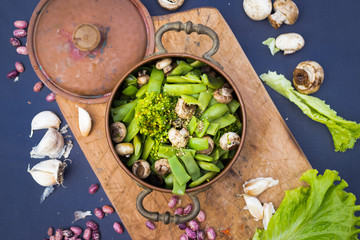 Cooked green beans, broccoli, mushrooms with spices. Cooked vegetables in copper vintage pot. Vegan vegetarian healthy food.