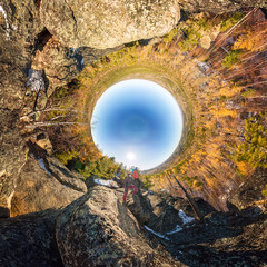 Couple of tourists with backpacks man and woman standing on a rock in autumn forest. tiny planet 360 panorama