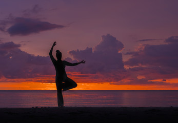 Silhouette of woman practice yoga on the beach at sunset
