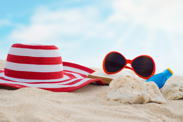 Sunglasses,hat,book,sunblock or suncreen lotion on sand beach