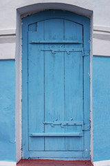 Vintage blue wooden door with white and blue house facade