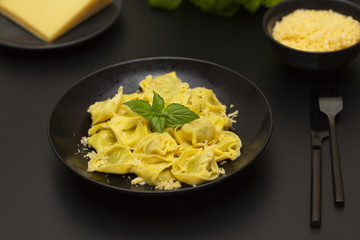 Traditional italian ravioli filled with ricotta cheese and spinach decorated with green leaves basil and grated parmesan