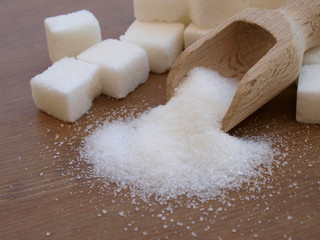 sugar adiction: sugar cubes and wood spoon over wood table