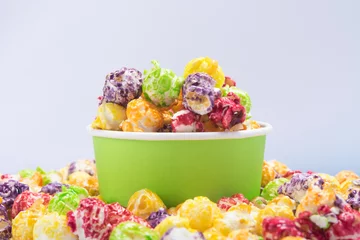 Crédence de cuisine en verre imprimé Buffet, Bar un seau de pop-corn multicolore se dresse dans un tas de céréales, sur fond blanc