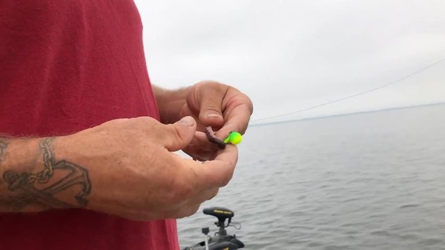Man preparing bait on fishing hook to go fish on boat