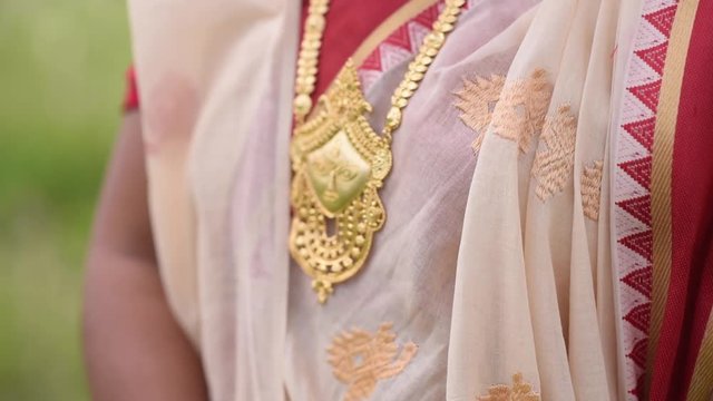 Indian woman wearing a gold necklace of a human face of Goddess Durga, close up