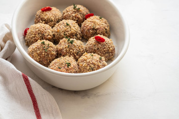 Raw fresh meatballs in the white plate on the white table. Copy space.