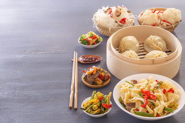 Dishes of Chinese cuisine in assortment. Steam dumplings, noodles, salads, vegetables, mushrooms, seafood. Copy space