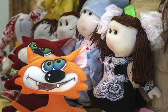 Children's dolls of cloth stand on the street counter for sale. Close-up