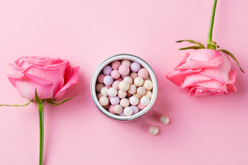 Cosmetic pearl make up powder with brush and fresh rose on pink pastel background. Top view.