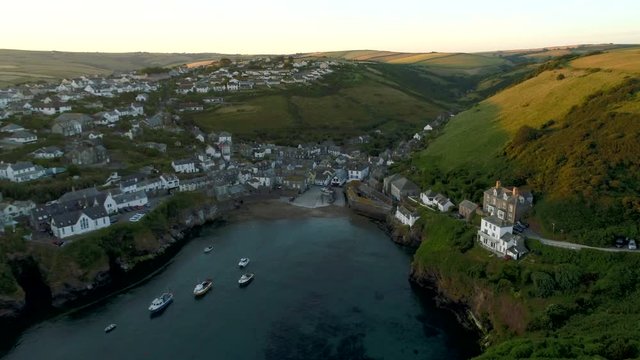 Drone flies slowly over harbor towards village of Port Isaac Cornwall