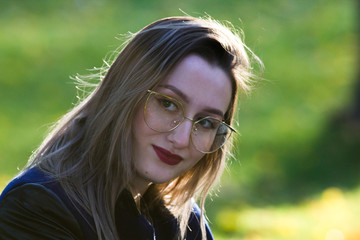 Beautiful girl in glasses with red lipstick looking in the camera. Natural contour lighting.