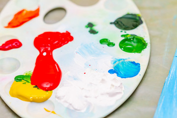Mixed multicolored paints on the palette. Closeup, selective focus