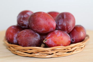 Ripe plums on straw plate