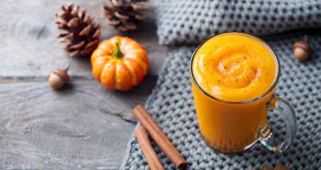 Pumpkin smoothie, latte with spices. Boozy cocktail on a wooden background. Copy space.