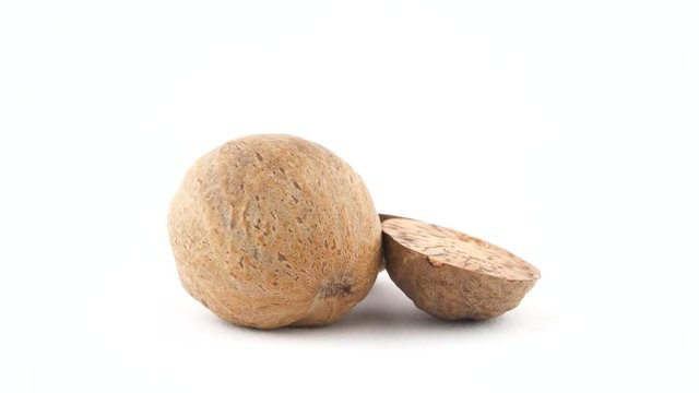 One whole and two nutmeg halves. Quickly rotating on the turntable isolated on the white background. Close up. Macro.