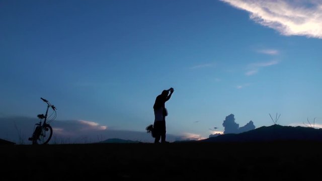 Silhouette of father and two daughter playing on mountain at sunset time.