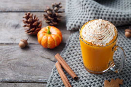 Pumpkin latte with spices. Boozy cocktail with whipped cream. Wooden background. Copy space.