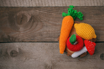 set of knitted toys lemon, carrot, apple, amanita on wooden background. Earlier tactile development of children, craft toys, vegetarian menu concept, copy space